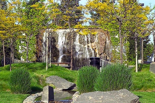 Peaceful waterfall cascading over rocks in a lush green park.